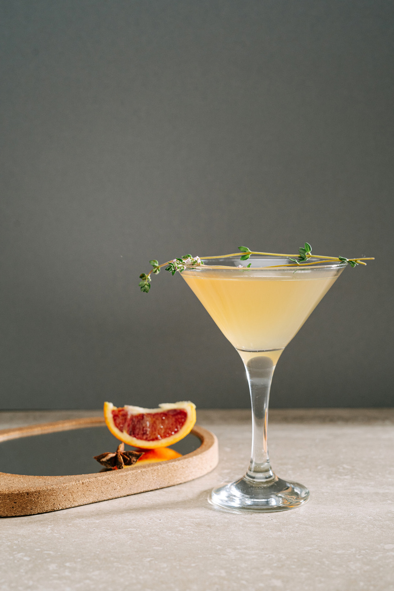 Clear Cocktail Glass With Yellow Liquid and Herbs